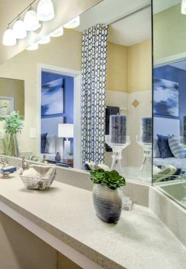 A bathroom with a large mirror, a sink, and a bedroom visible through the door.