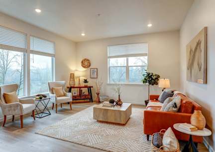 A living room with a red couch, a wooden coffee table, and a large window with blinds.