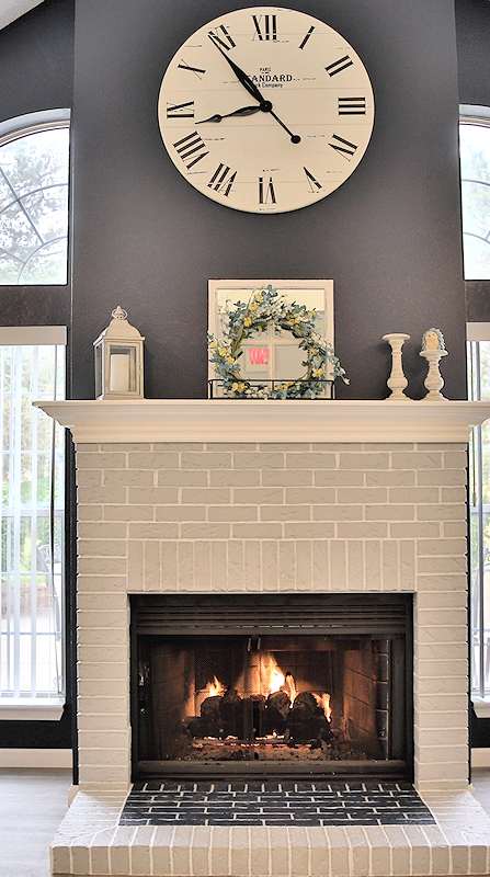 a living room with two chairs and a fireplace with a large clock on the wall