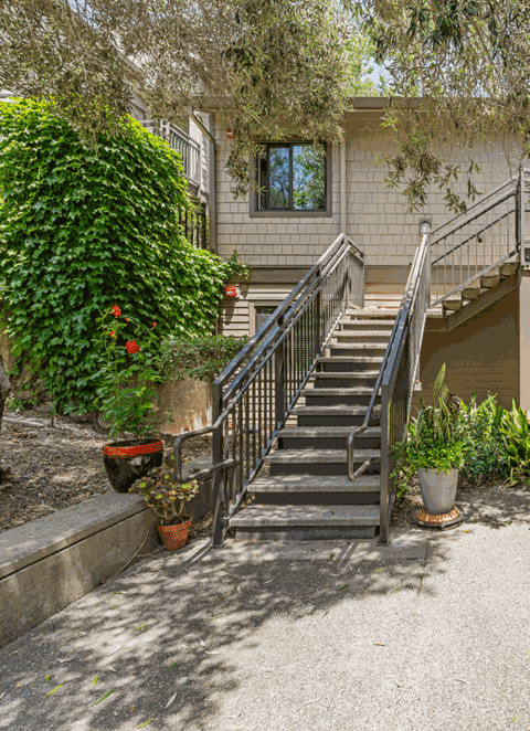 the entrance to a house with stairs and a yard with plants