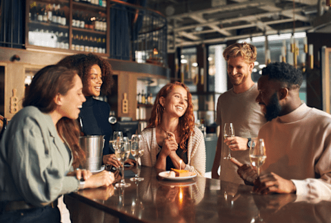 A group of people are gathered around a bar counter, enjoying drinks and conversation. at Tides on East Cactus Apartments, Arizona, 85032