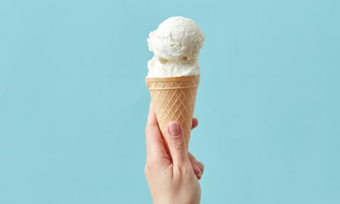 a hand holding a cone with a scoop of vanilla ice cream at The Villages Apartment of Bayan Grove in Boynton Beach, FL