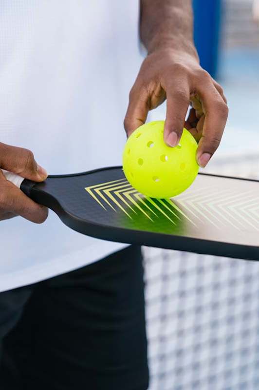 Close-up of resident holding a pickleball paddle and ball at an outdoor court, highlighting active lifestyle amenity at an apartment community.