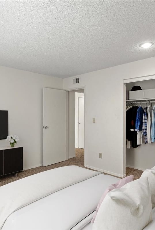 a bedroom with a large white bed and a tv