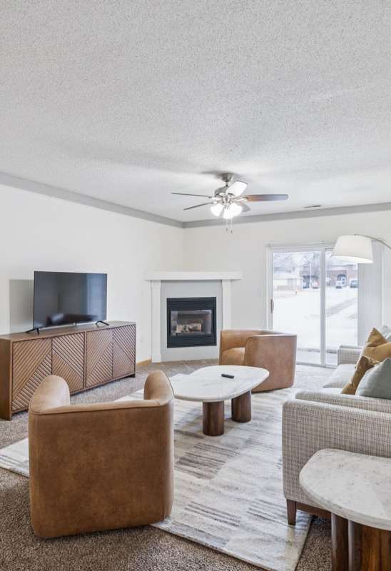 A living room with a brown couch, a brown chair, and a brown rug.