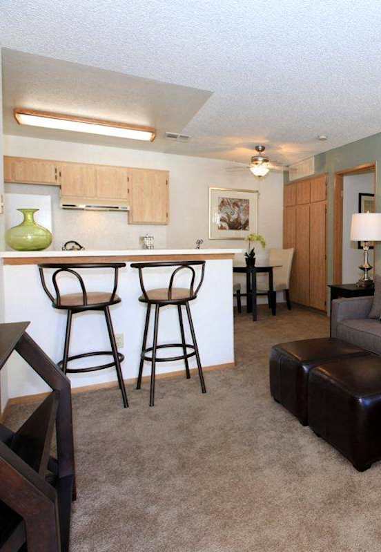 a living room with a couch and a kitchen with a bar at Victoria Springs Apartments, Riverside