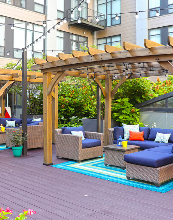 a seating area under a wooden pergola on a patio at The Laurel Apartments, Saint Louis, MO