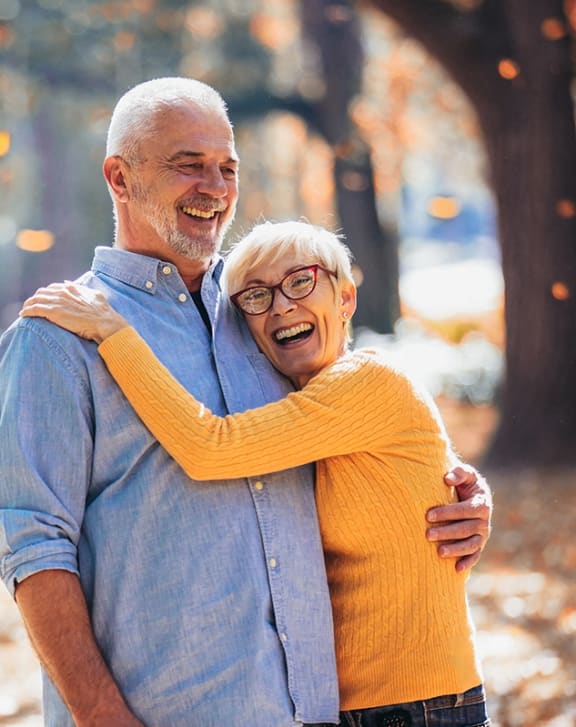 an older man and woman smiling and hugging each other