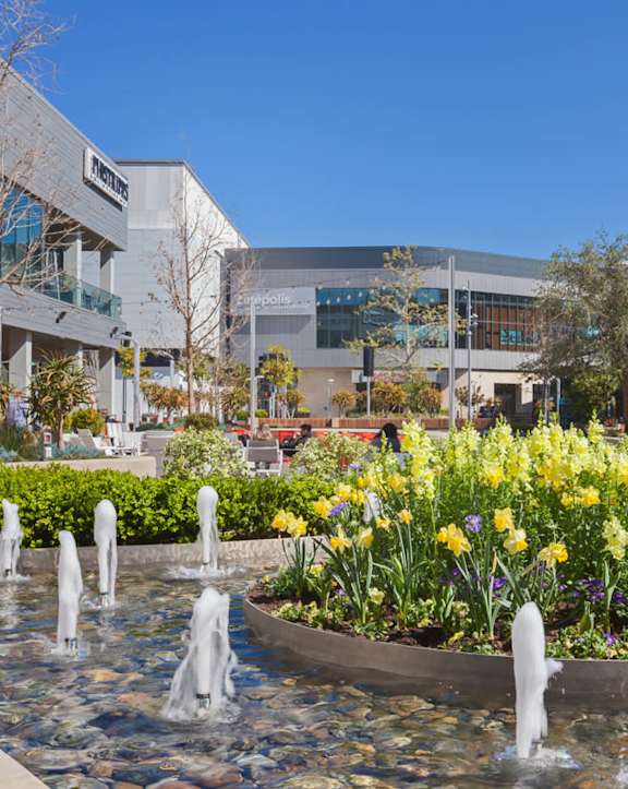 a fountain in front of a building with two flags
