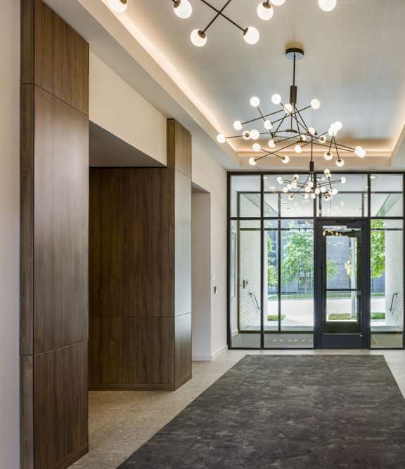 A hallway with a black carpet and a chandelier.