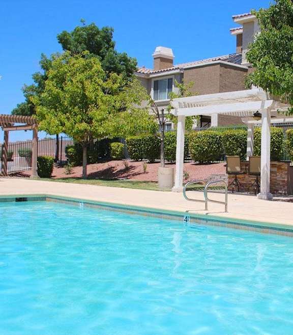 A pool with a white pergola and trees in the background at Avalon at Seven Hills Apartments, Henderson, 91790