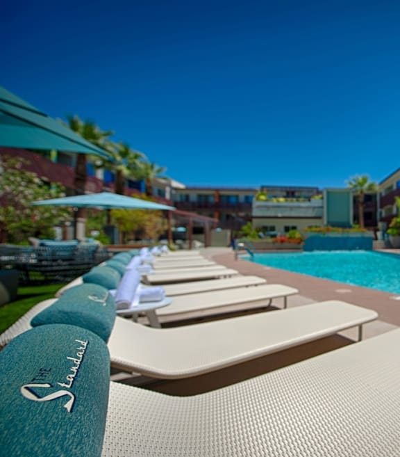 a pool with lounge chairs and umbrellas in front of a hotel