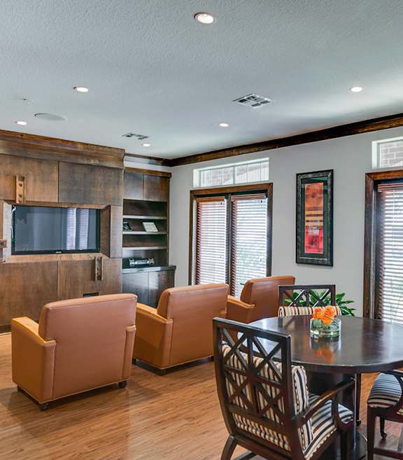 A living room with a grey couch and a flat screen TV mounted on the wall.