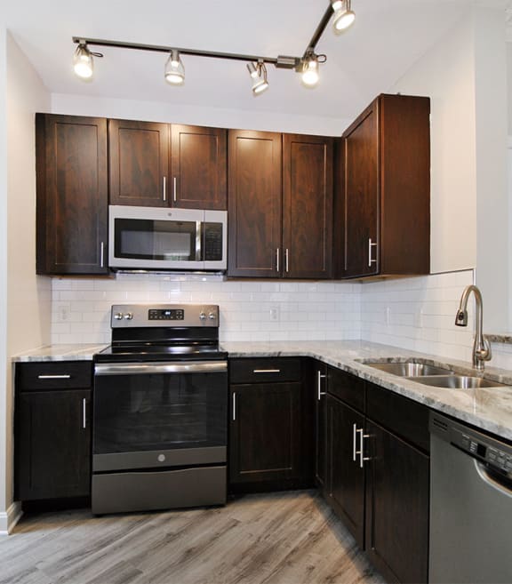a kitchen with dark wood cabinets and white countertops