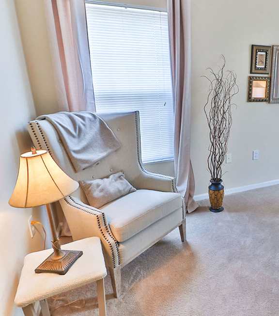A bedroom with a bed, chair, and nightstand.