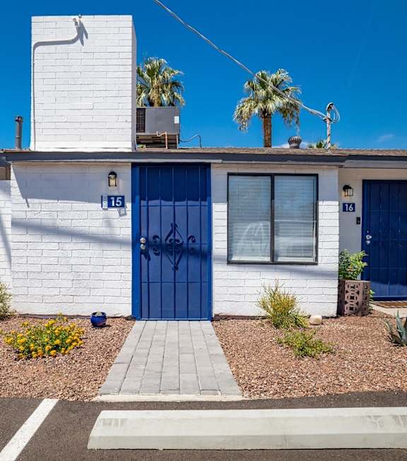 A white house with a blue door and a small garden in front.