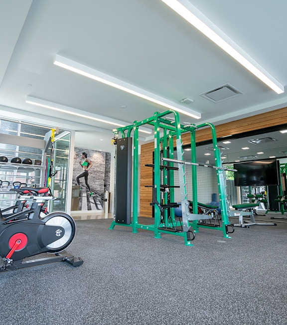 A gym with a variety of equipment including a stationary bike and a leg press machine.