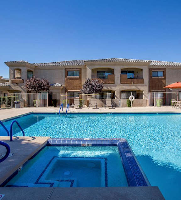A large swimming pool in front of a building with a clear blue sky at Sereno Townhomes, Glendale, AZ.