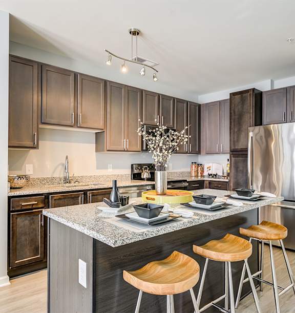 a kitchen with a large island with three stools in front of it at Ascend Apollo Apartments, Largo, Maryland