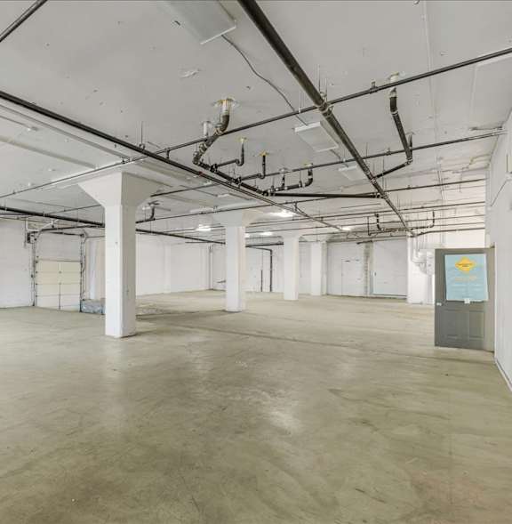 A large, empty warehouse with a concrete floor and white walls.