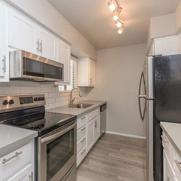 A kitchen with white cabinets and black appliances.