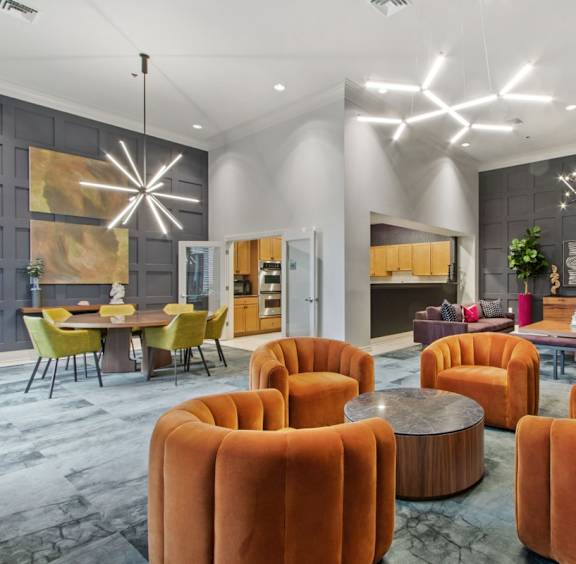 A modern living room with orange chairs and a grey wall.