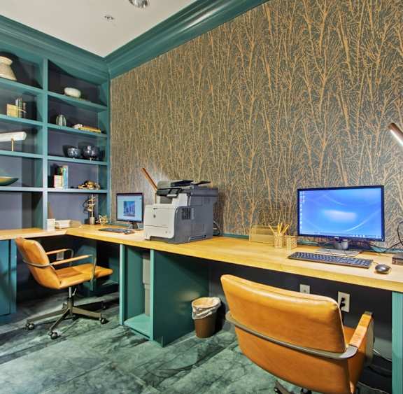 A computer desk with a blue screen monitor and a brown chair.