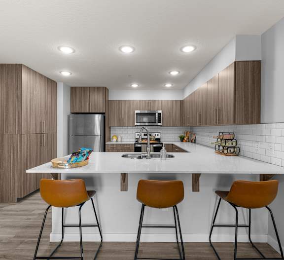 A modern kitchen with a white table and brown chairs.