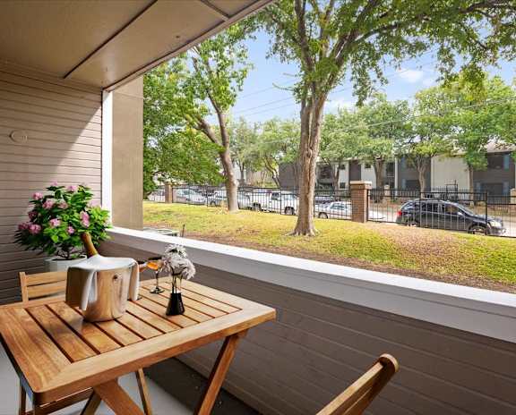 a balcony with a wooden table and two chairs and a large window with a view of a