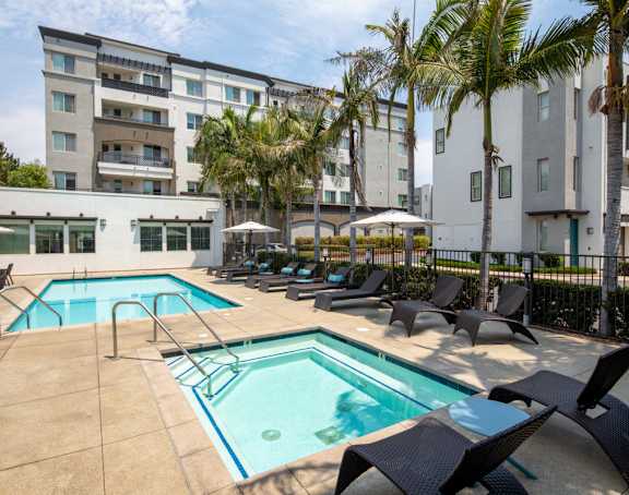 A large swimming pool surrounded by lounge chairs and palm trees.