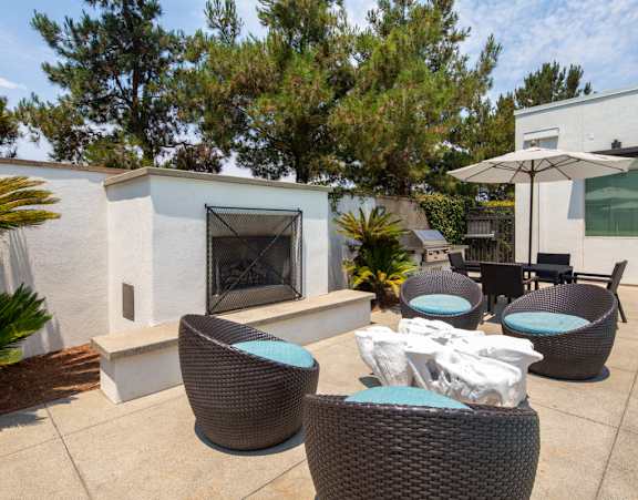 A patio with a fireplace and chairs.