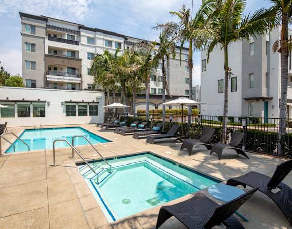 A large swimming pool surrounded by lounge chairs and palm trees.
