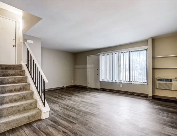an empty living room with a staircase and a window