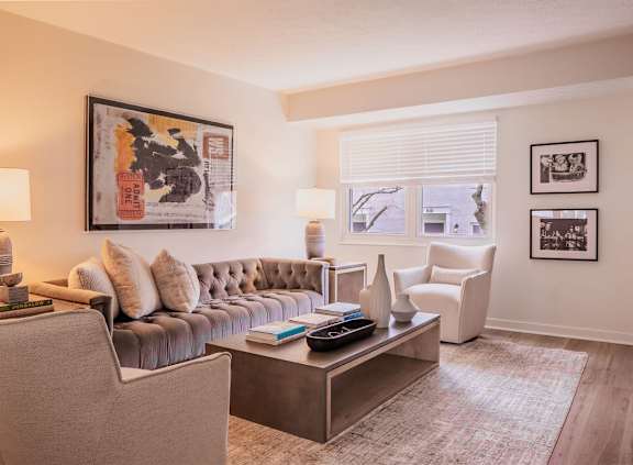 A living room with a grey couch, a coffee table, and a painting on the wall.