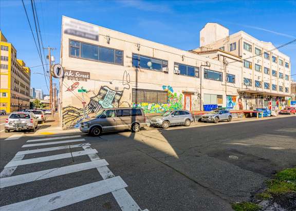 A street view with cars, a crosswalk, and a building with a mural on the side.