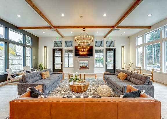 A large, well-lit living room with a central sectional sofa and a chandelier hanging from the ceiling.