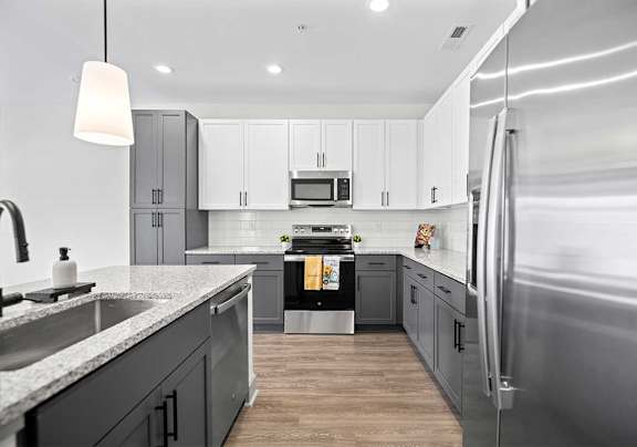 A modern kitchen with a stainless steel refrigerator and wooden floors.