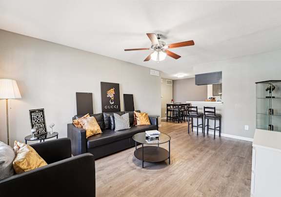 A living room with a black couch and a ceiling fan.