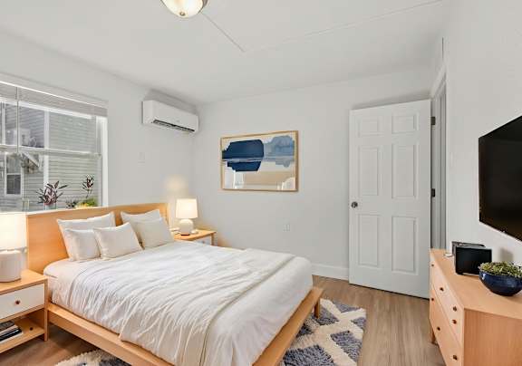 A bedroom with a bed, nightstands, and a painting on the wall.