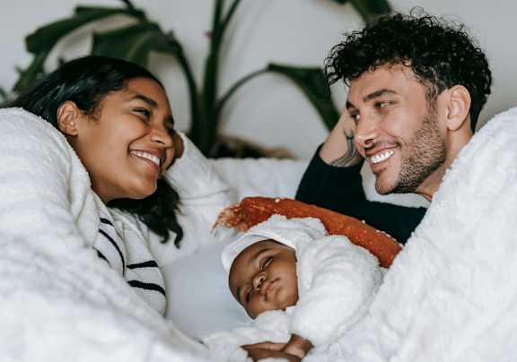 A family of three is lying in bed together.