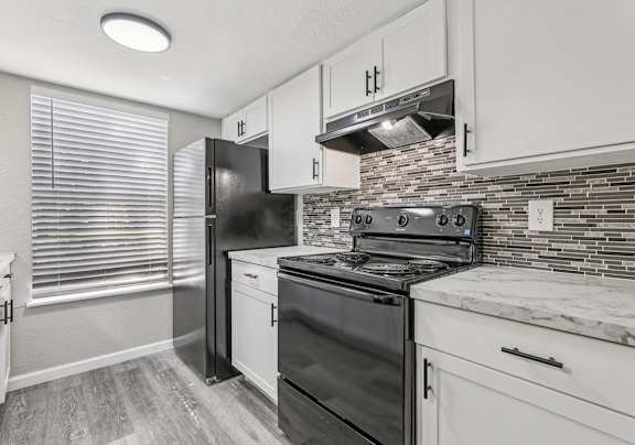 A kitchen with black appliances and white cabinets.