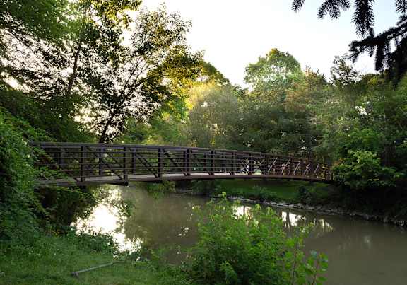 A bridge over a river surrounded by greenery.