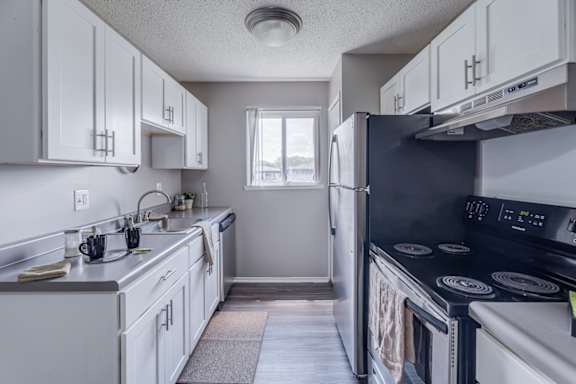 A kitchen with white cabinets and a black refrigerator.