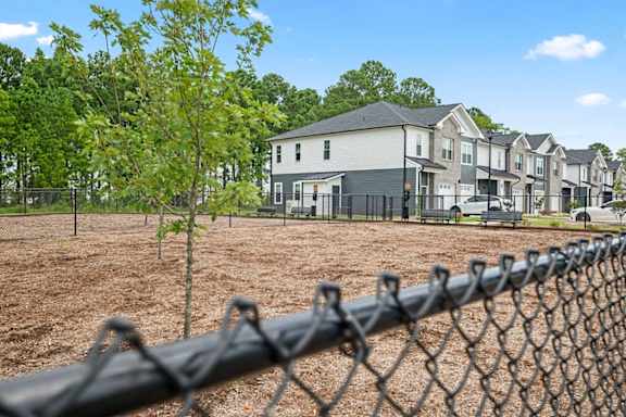 A chain link fence in front of a row of houses.