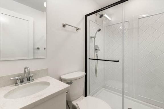 A white bathroom with a sink, toilet, and shower.