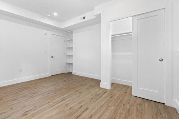 A room with white walls and wooden flooring with a door on the right.
