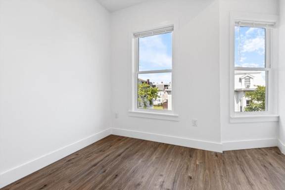 A room with two windows and wooden flooring.