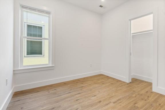 A room with a window and wooden flooring.
