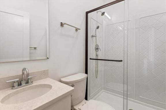 A white bathroom with a sink, toilet and shower.