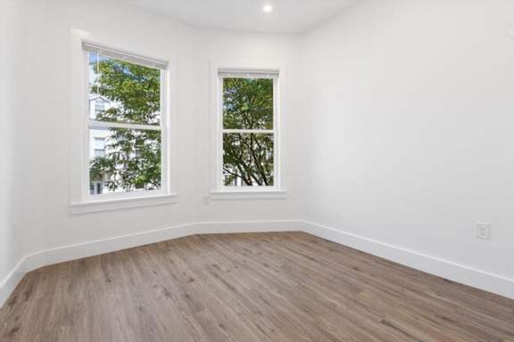 A room with two windows and wooden flooring.